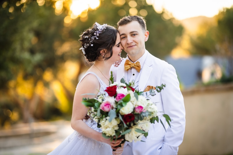 Elopement Photographer, a bride with bouquet kisses her groom on the street outside at golden hour